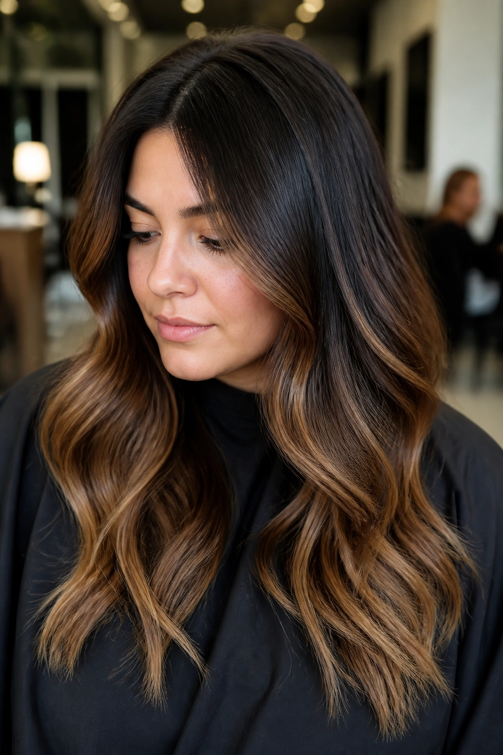 Close-up of a real person with deep root shadow balayage and caramel ends, natural salon lighting.