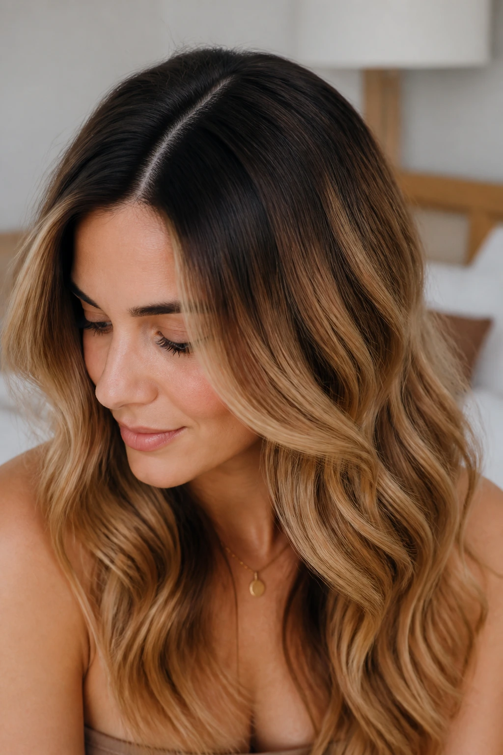 Close-up portrait of a real woman with rooted honey brown waves and a dark root on cool skin tones.