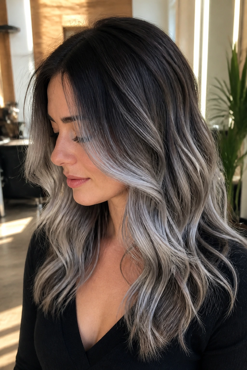 Close-up of a real woman with rooted shadow melt silver hair transitioning from dark brown roots to steel-gray mids and silver ends