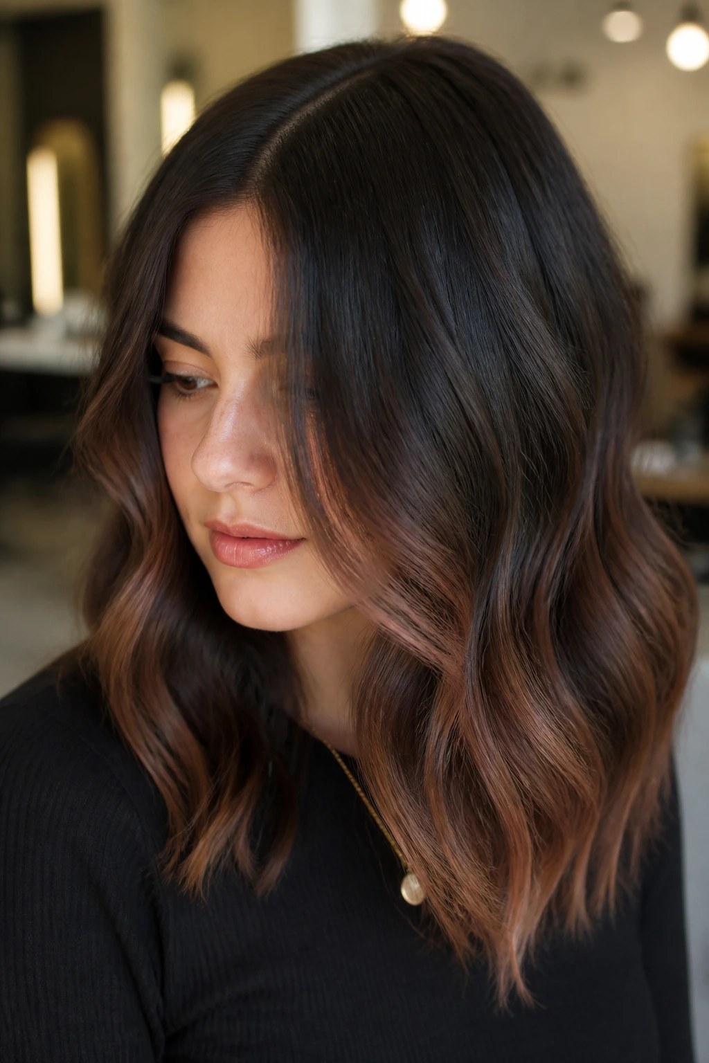 Close-up of real person with dark brown hair and subtle rose gold gloss in bright indoor light
