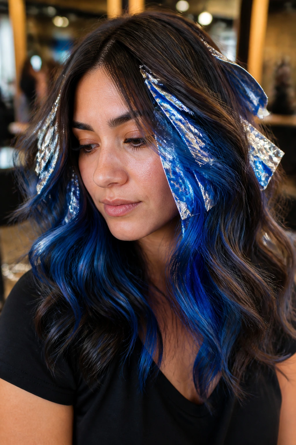 Close-up of a real woman with royal blue foilyage on brown hair in a salon