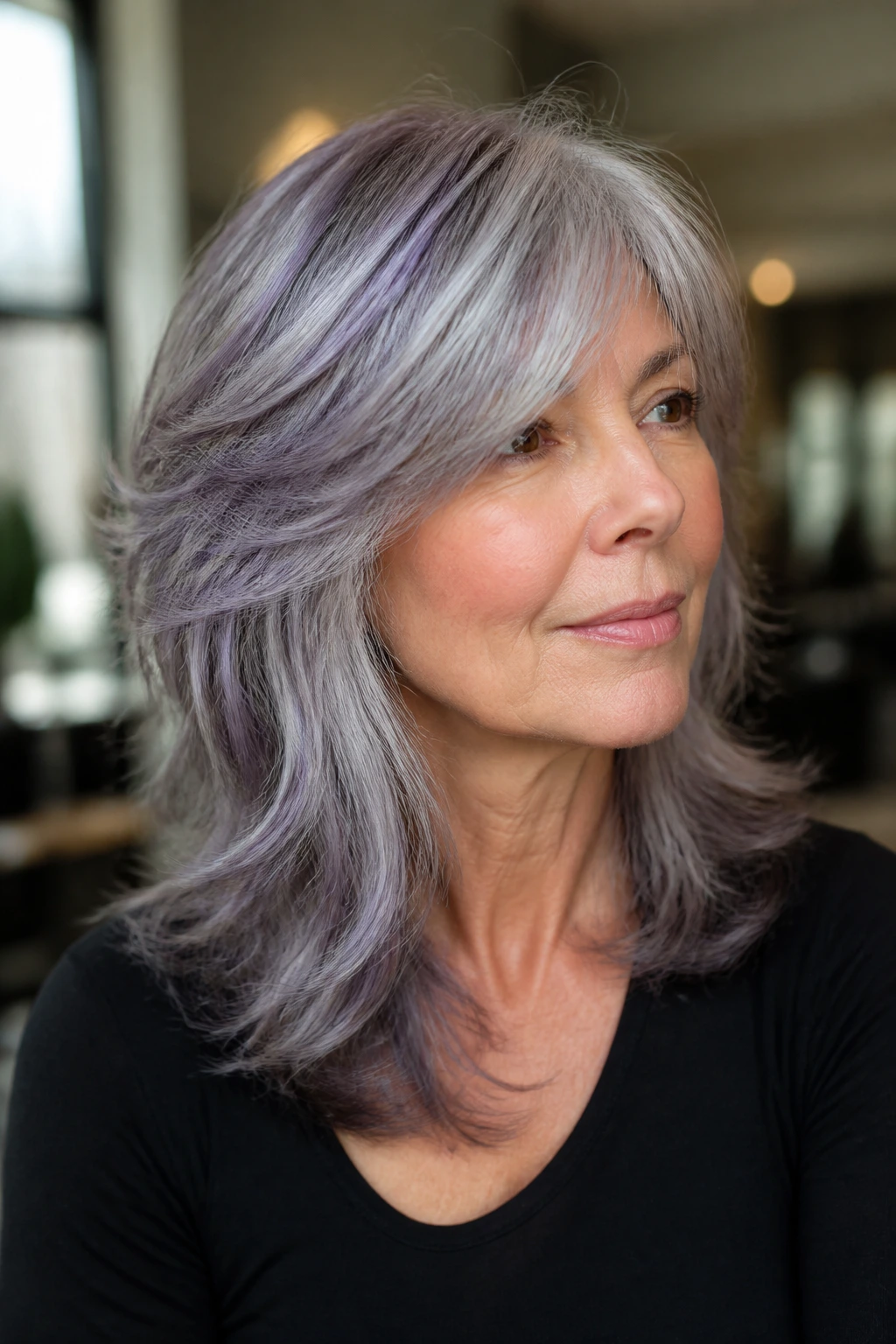 Real woman with salt-and-pepper shag and violet toner in a bright salon