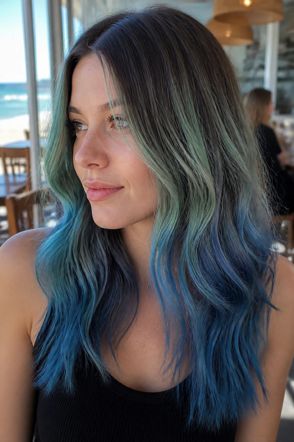 Close-up of brown hair with seafoam to blue gradient in natural light.