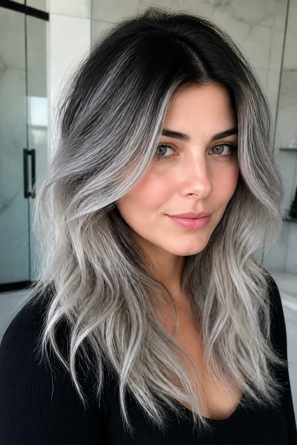 Close-up of a real person's hair showing a cool shadow root and silver lengths in natural bathroom light.