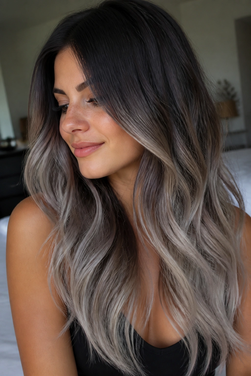 Close-up portrait of a real woman with long brunette hair showing a soft shadow-root silver melt