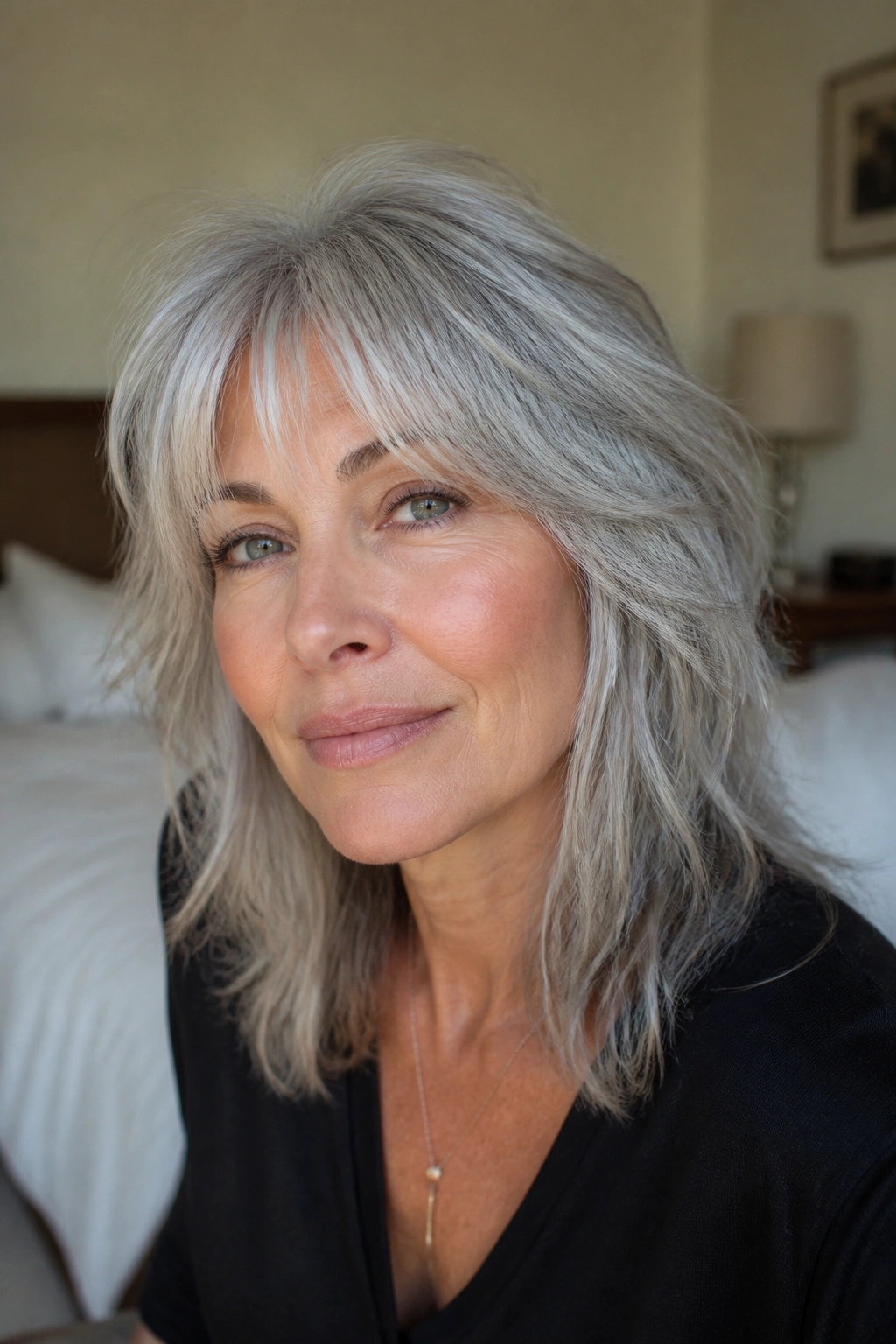 Close-up portrait of a real woman with silver shag and wispy curtain bangs in natural window light