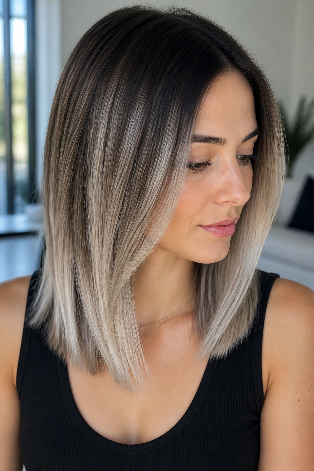 Real woman with straight mid-length hair showing silver balayage and brighter underlayers.