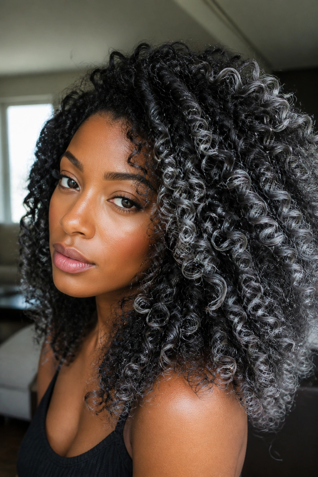 Close-up of real woman with natural curls showing silver dust on the outer curves for dimensional ombre