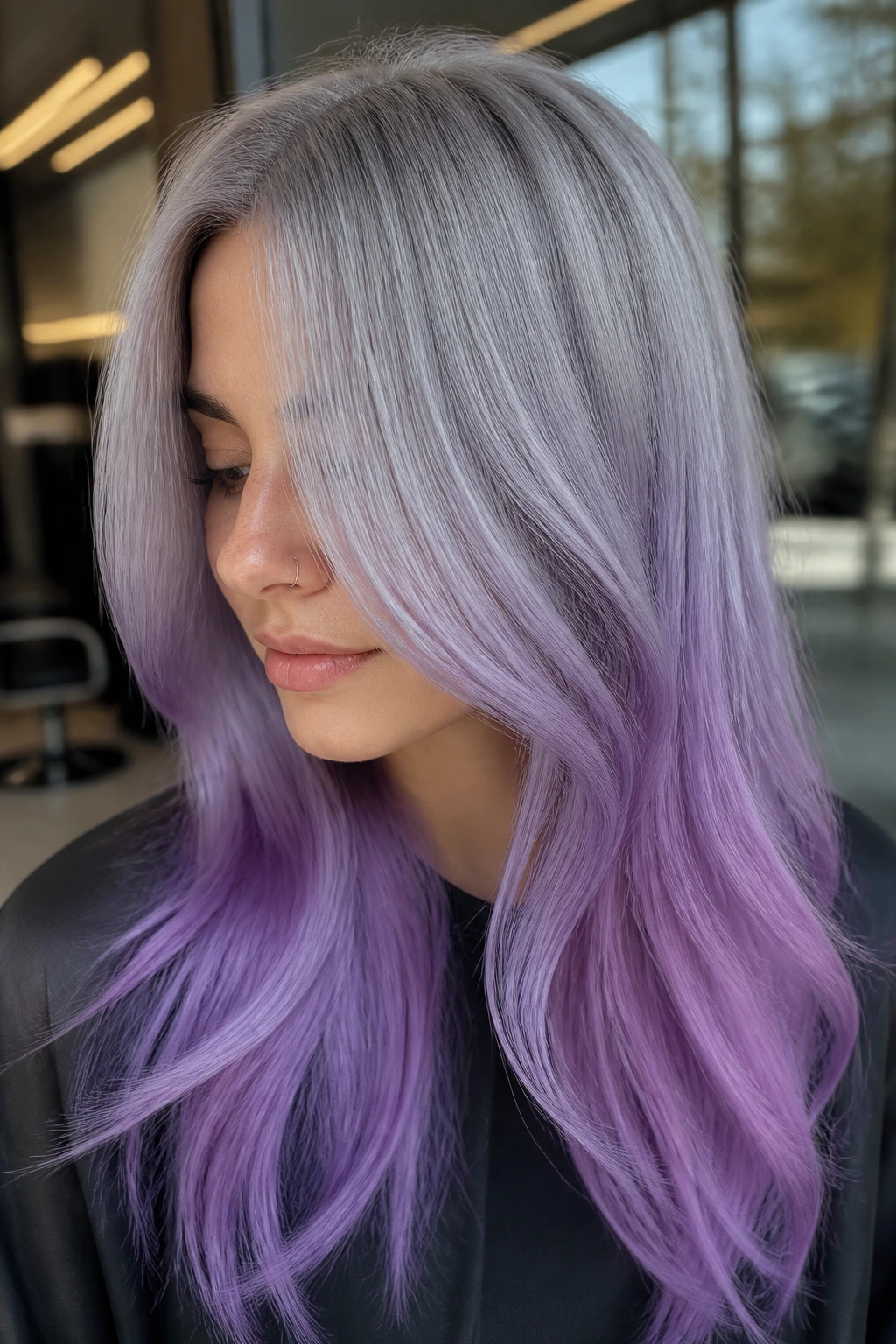 Close-up portrait of a real woman with silver to pastel purple ombre on long hair in a salon