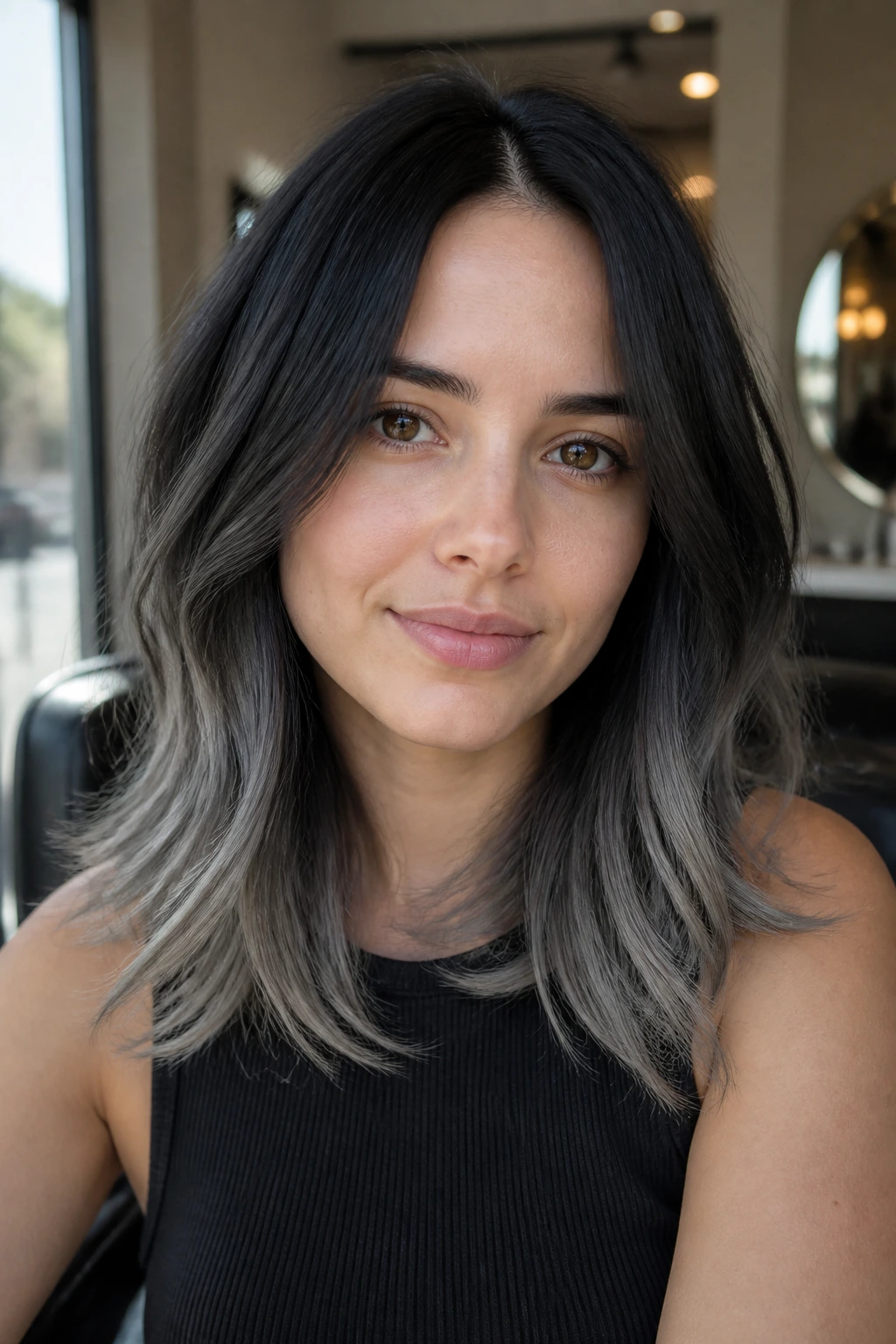Close-up of a person with black hair fading to slate-gray ends, smooth gradient.
