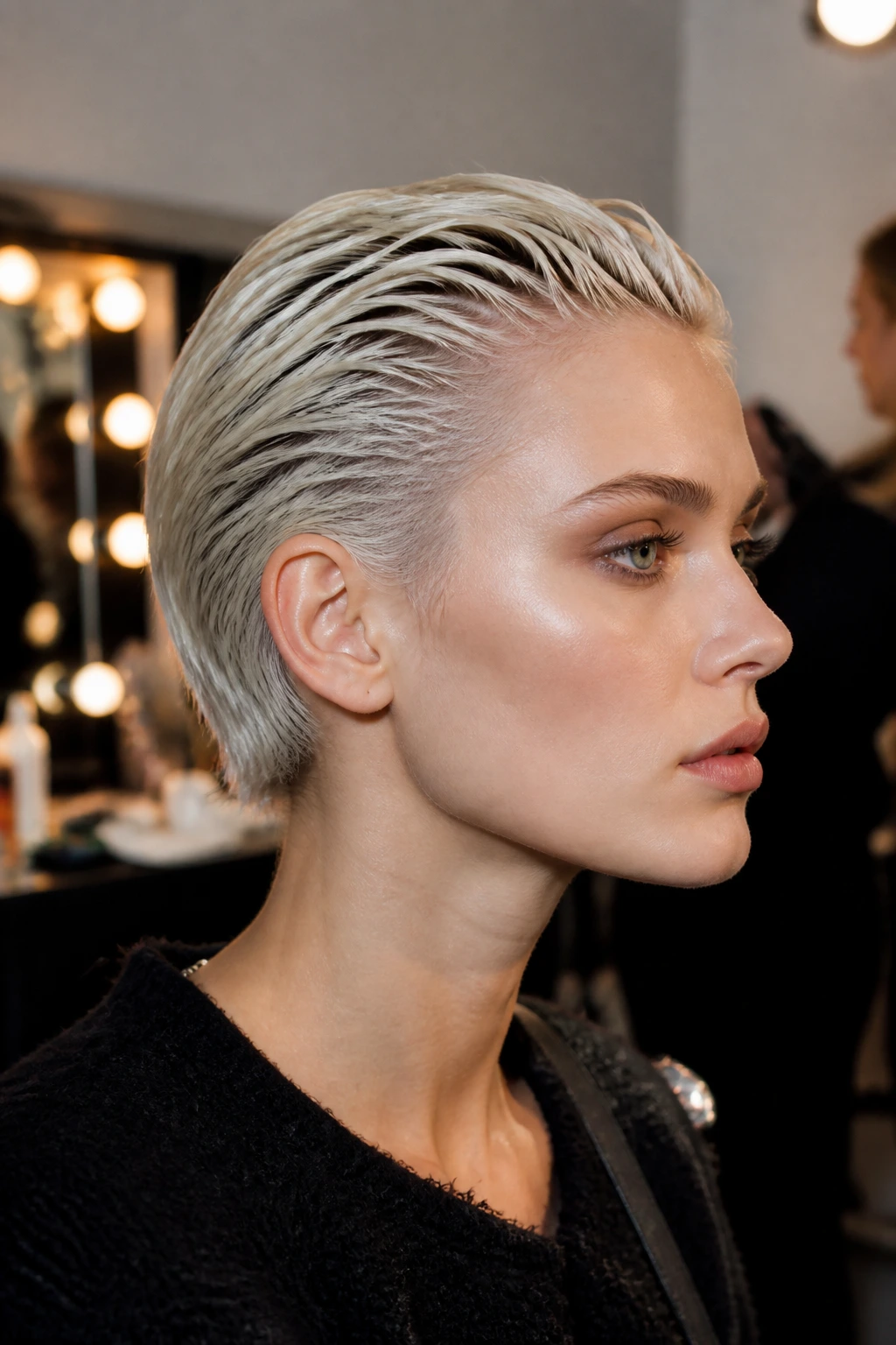 Close-up portrait of a real woman with slicked-back wet-look pixie in platinum.