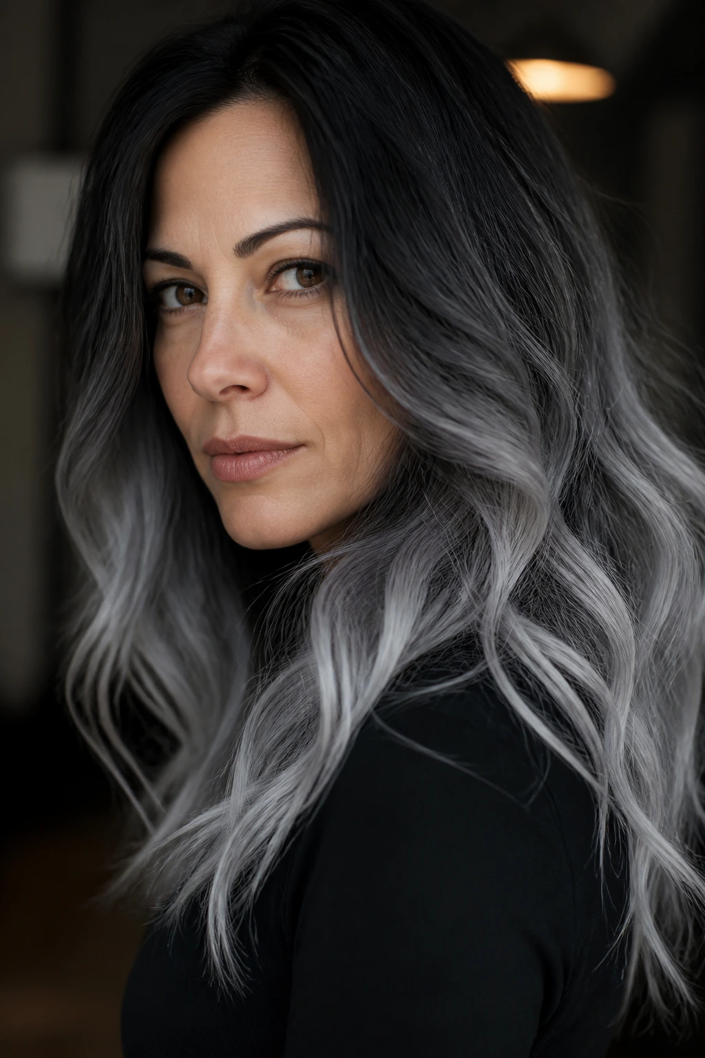 Person with smoke-black gradient hair in a dimly lit chic interior