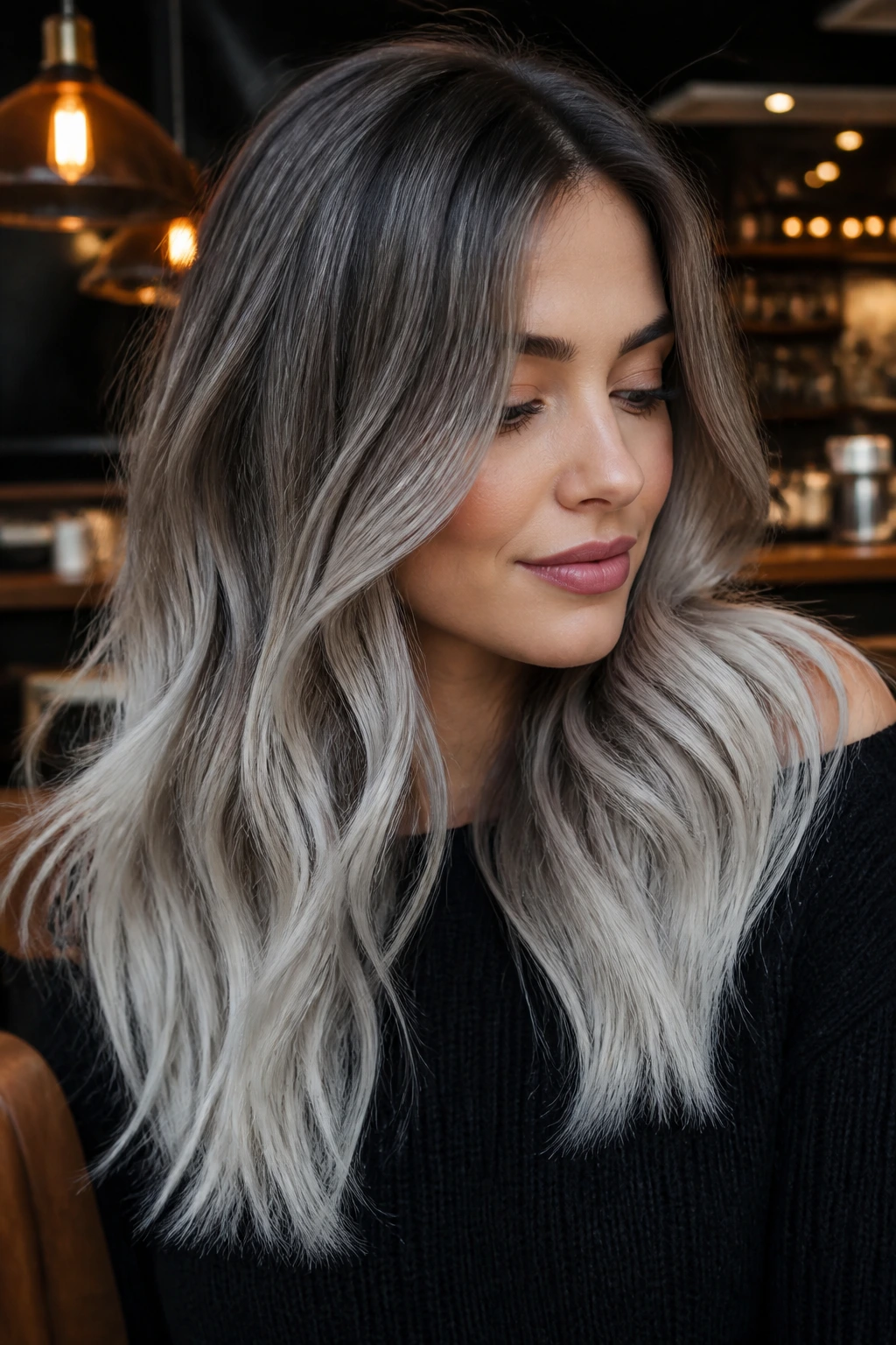 Close-up portrait of a real woman with smoky-to-silver hair in a cafe setting.