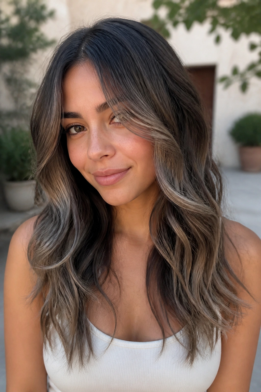 Close-up of a woman with smoky brunette balayage featuring cool root and ash-beige ends