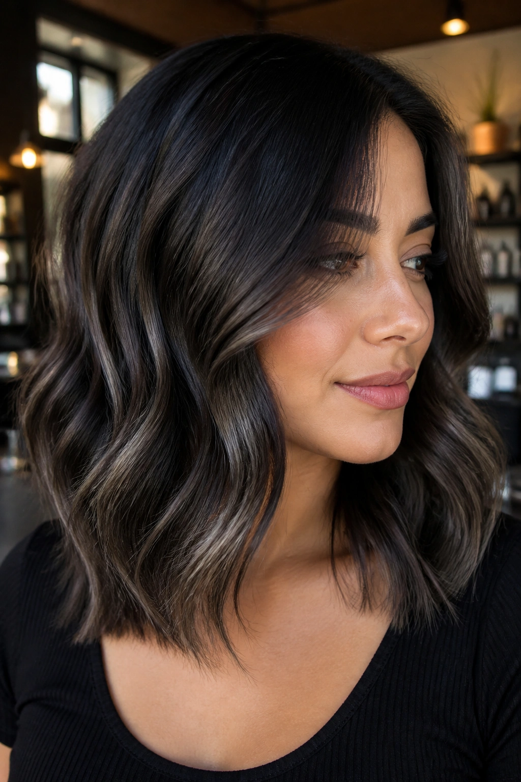 Close-up portrait of a real woman with medium-length wavy hair featuring smoky black balayage
