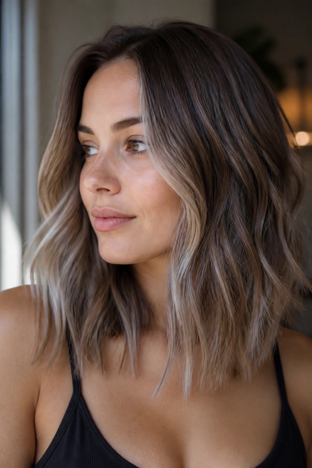 Close-up of a real woman with smoky beige brunette balayage in natural window light