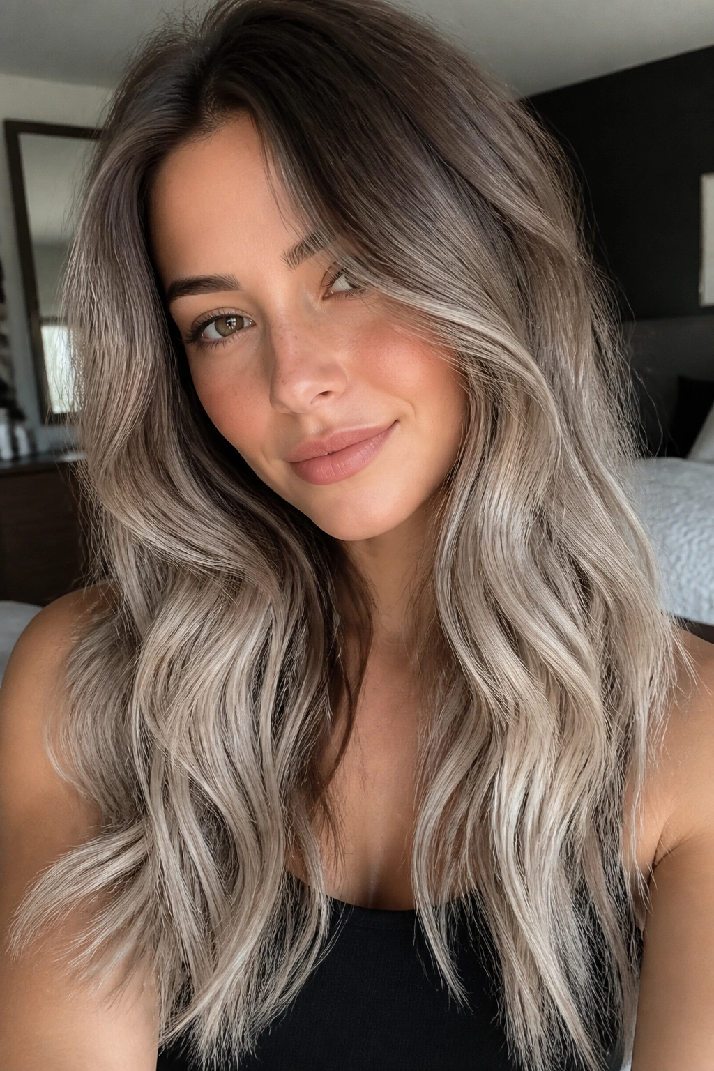 Portrait of a real woman with smoky brunette roots fading to pearl blonde ends in long waves
