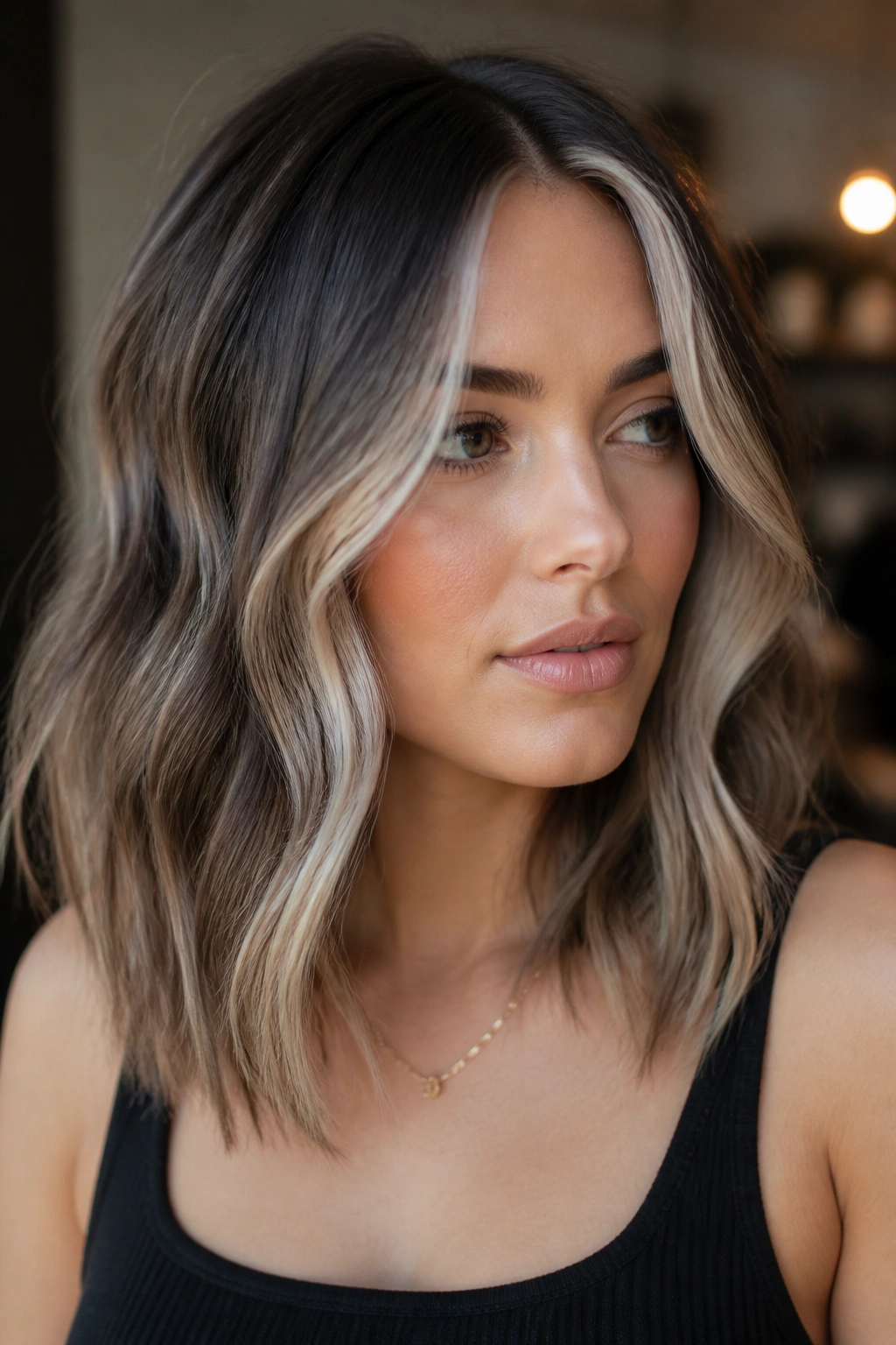 Close-up portrait of a woman with smoky mocha hair and pearl face-framing pieces.