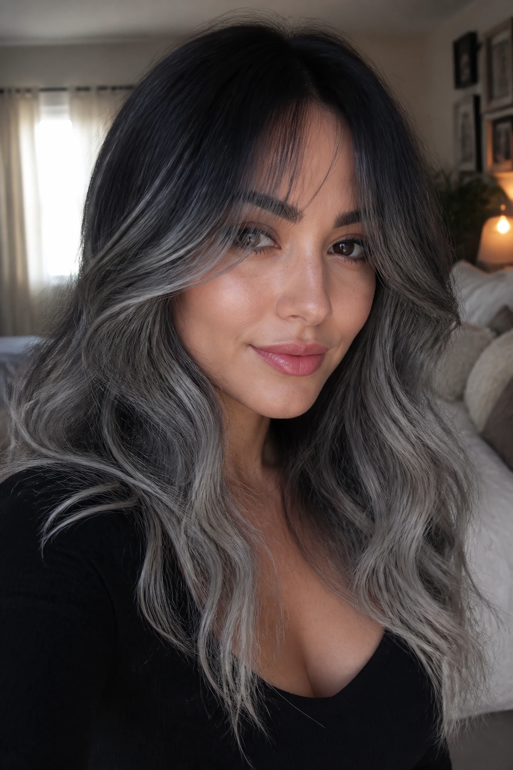 Close-up portrait of a woman with smoky gray ombre and curtain bangs in warm bedroom light