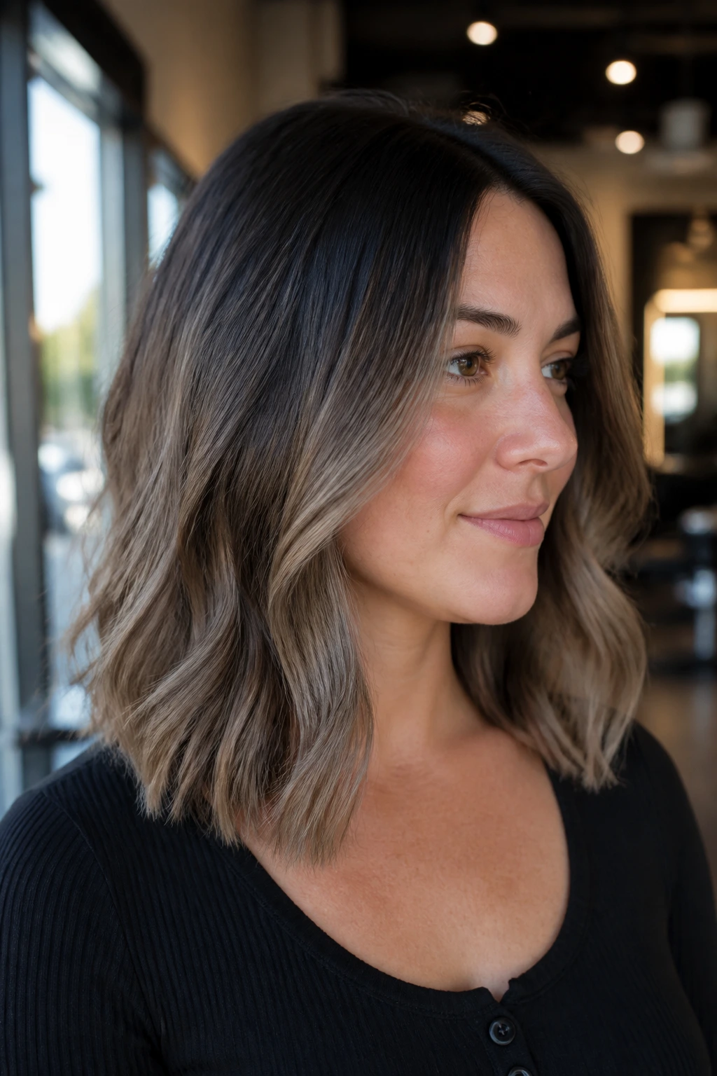 Medium close-up of a real woman showing smoky root melt on a long lob with ash brown balayage.