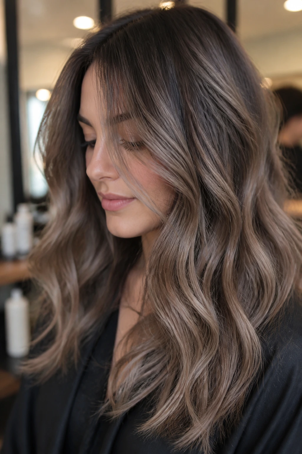Close-up portrait of a real person with smoky taupe balayage on wavy hair