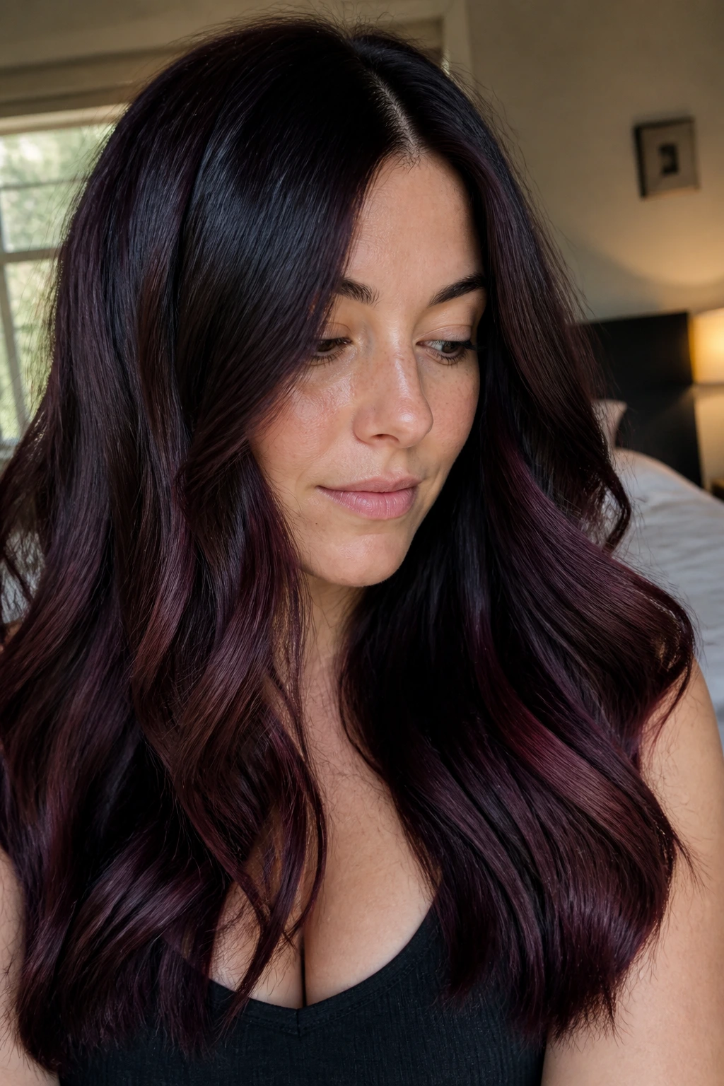 Close-up of a real woman with soft black cherry melt hair under window light