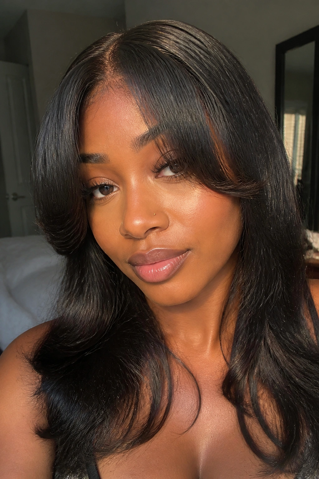 Close-up portrait of a real woman with soft curtain bangs framing the forehead in a frontal weave, warm window light.
