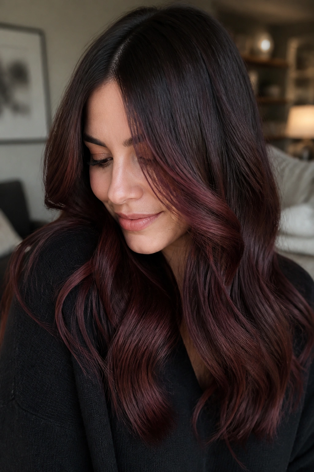 Close-up of a real woman with soft wine brunette balayage under warm light