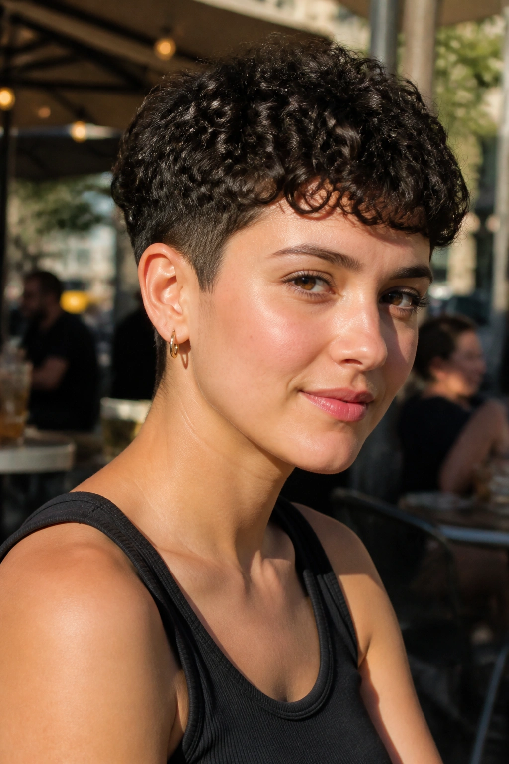 Real person with a tapered curly crop in outdoor cafe light.