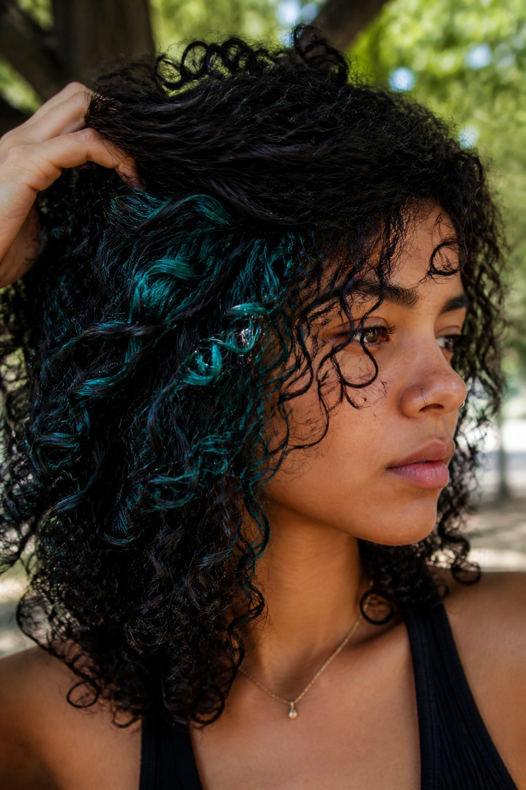 Close-up of black curls with teal hidden panels seen as curls separate in an outdoor park