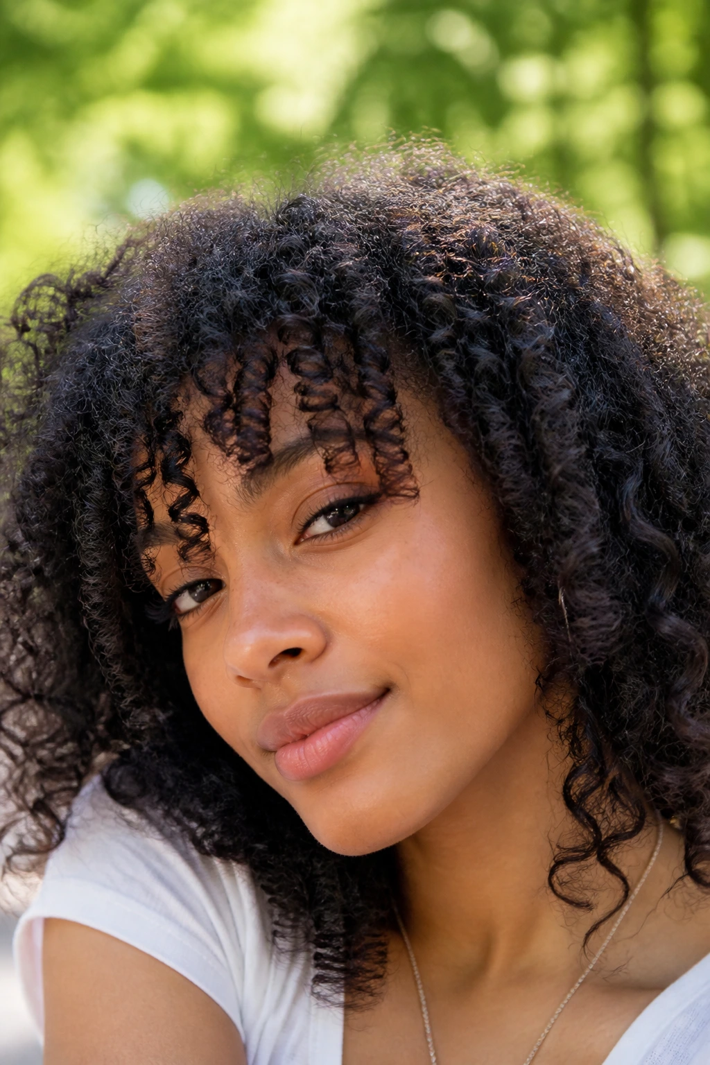 Close-up of a woman with textured bangs on curly hair outdoors