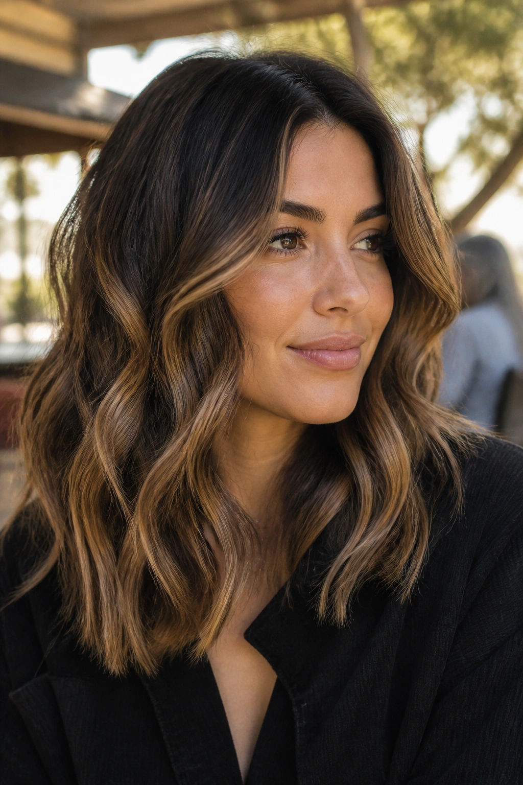 Wavy midlength hair with toffee swirls around cheeks in golden hour light.