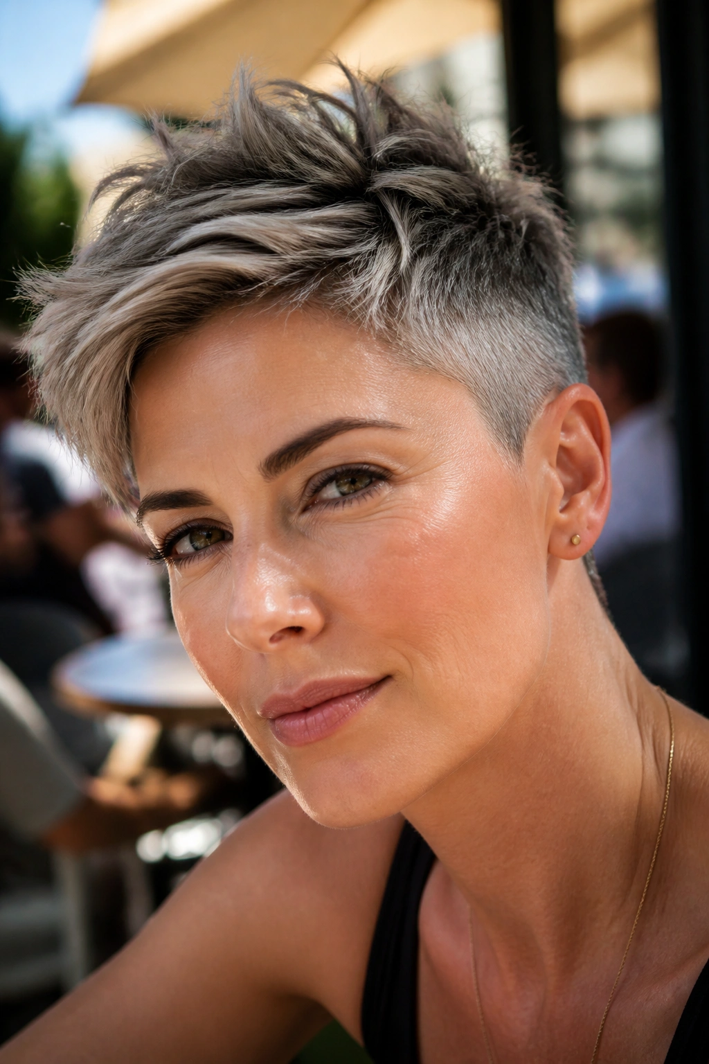 Portrait of a real woman with an undercut pixie and feathered top in a sidewalk cafe setting
