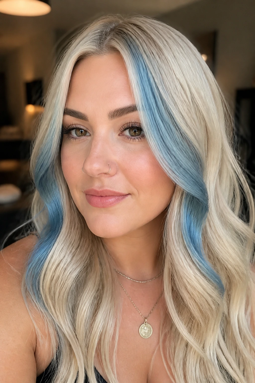 Close-up portrait of a real woman with vanilla blonde hair and steel-blue money pieces framing the face