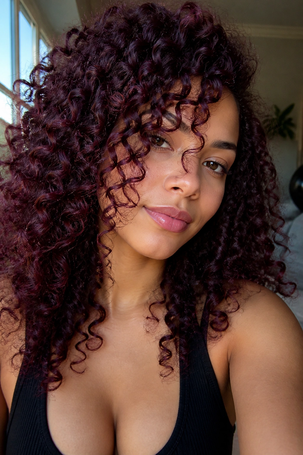 Close-up portrait of a woman with velvet black cherry curls in natural light