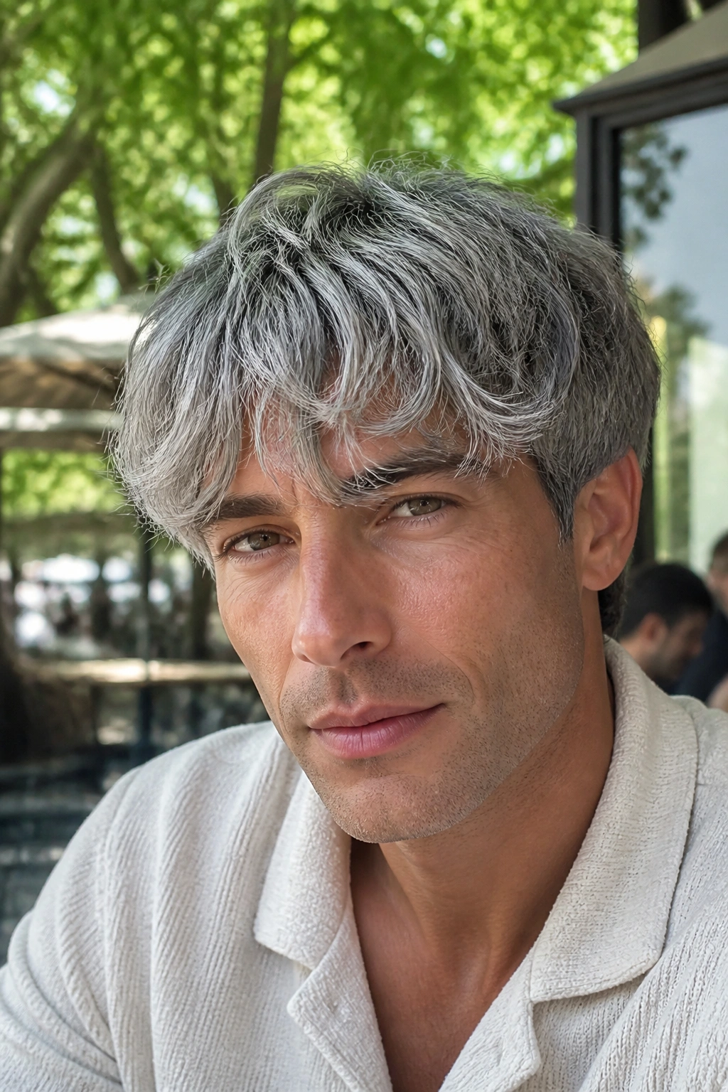 Close-up portrait of a man with wavy silver fringe in natural light