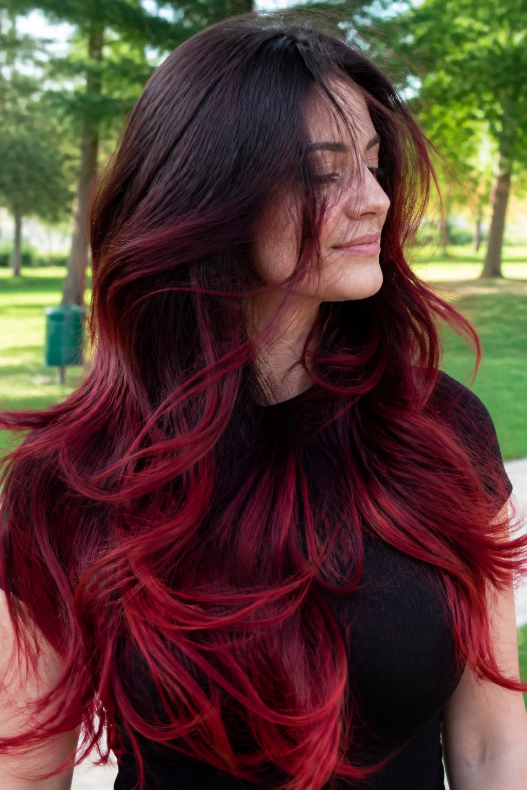 Windblown cherry red ombre on long layered hair of a real woman outdoors
