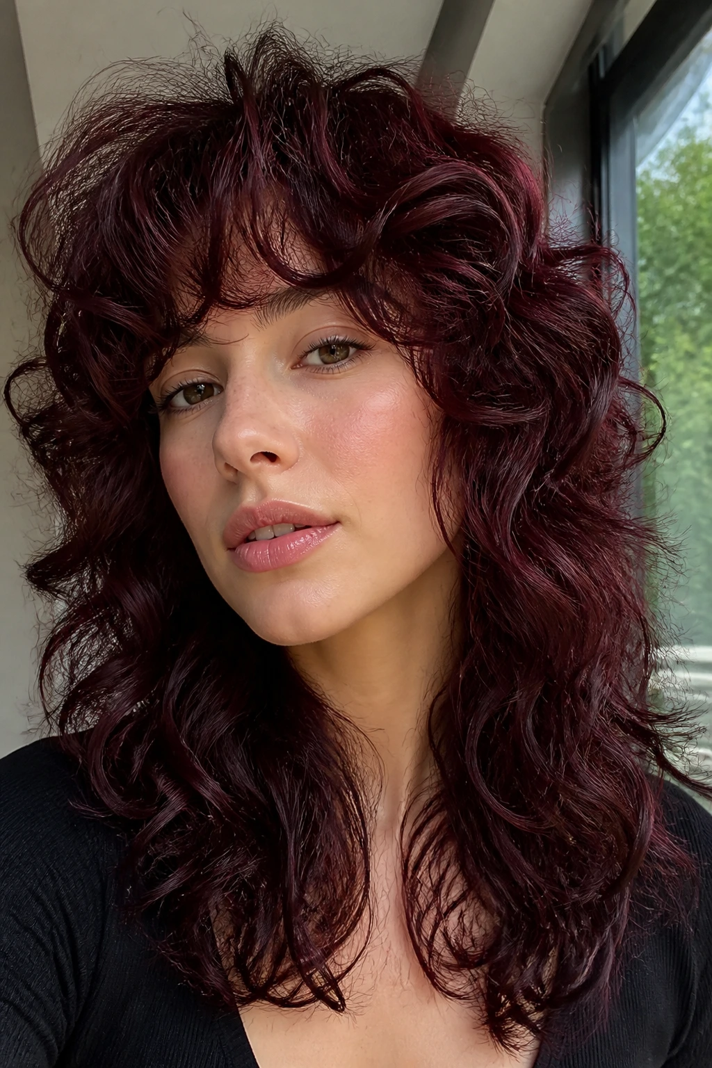 Close-up of a real person with wine mahogany curly shag hairstyle