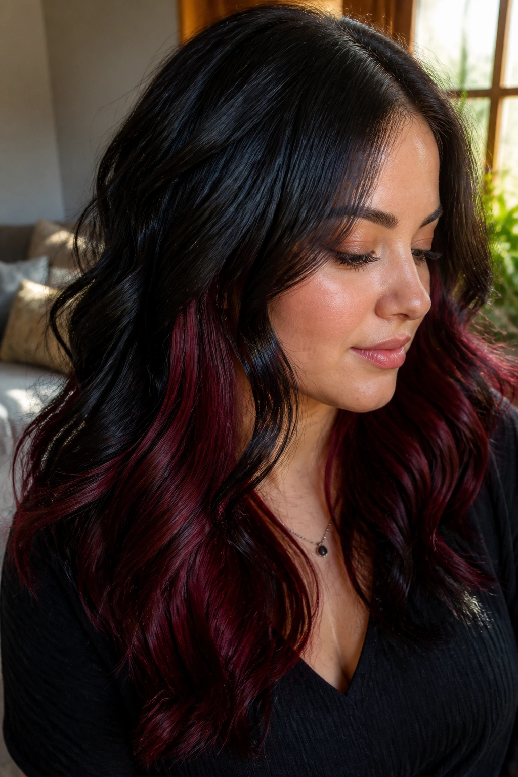 Close-up of a real woman's wavy black hair with wine-red underlayers visible as waves bend.