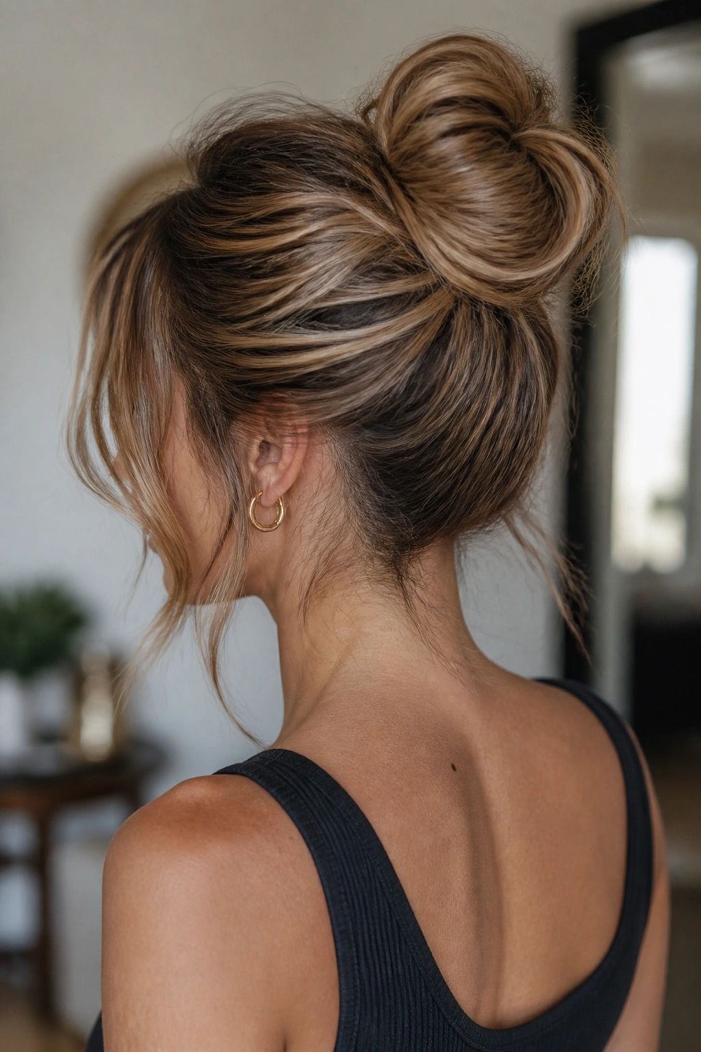 Back-facing close-up of a real person with a wrapped top knot on shoulder-length layers.